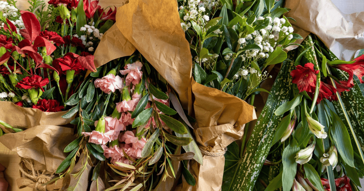 A bunch of red and white flowers are wrapped in brown paper.